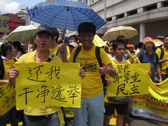 Ethnic Chinese hold up signs reading 'Give us a clean choice' and 'Police chief, please respect democracy'