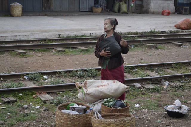 An old woman, waits, watches on the train tracks