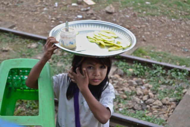 A girl sells slices of melon to passengers on the train